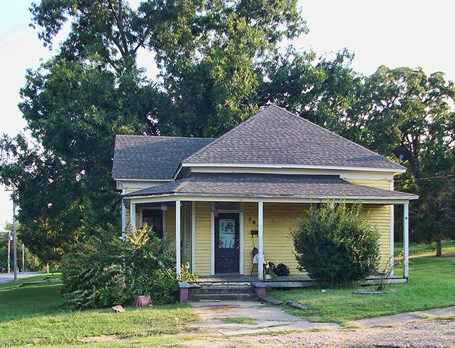 House with yellow paint and covered porch on street corner
