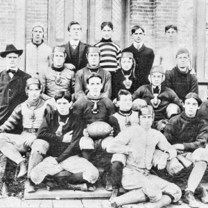 Young white men some wearing helmets posing for a group photo sitting on steps