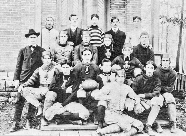 Young white men some wearing helmets posing for a group photo sitting on steps