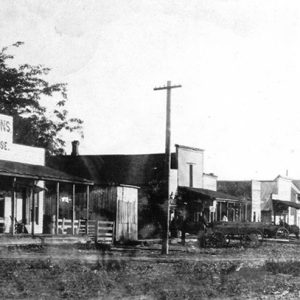 street scene with various storefronts and horse drawn carts