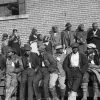 Group of African-American men and women with identification tags waiting outside brick building