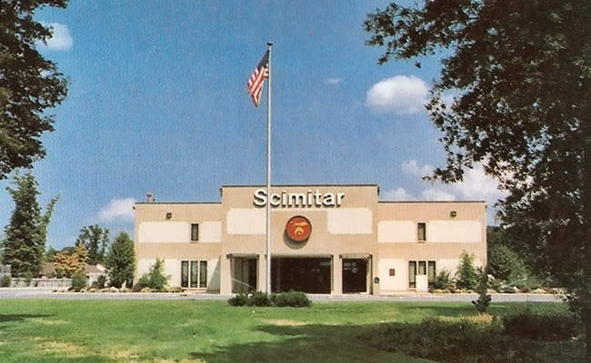 Two-story building with "Scimitar" logo and flag pole