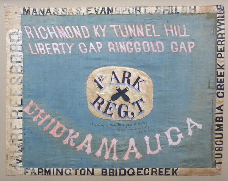Flag with crossed cannons on white "first Arkansas regiment" logo on blue background with white and black text
