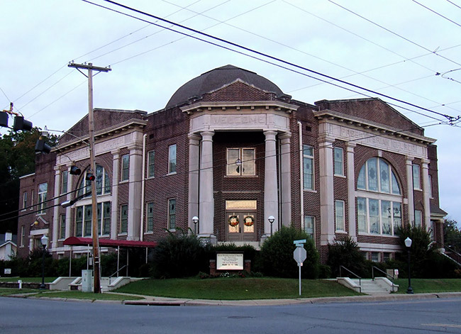 Two-story brick building with columns and arched windows on street corner