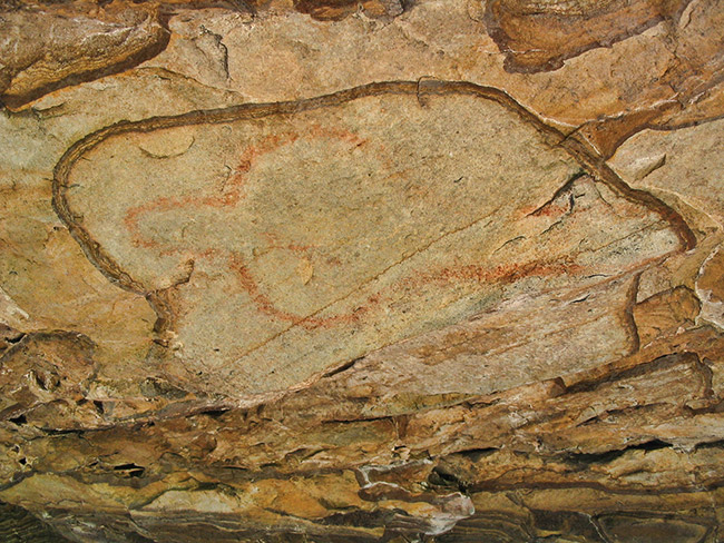 Faded red cave painting on rock wall
