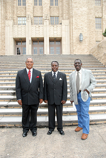 three African American men stand in front of stone steps leading to multistory stone building