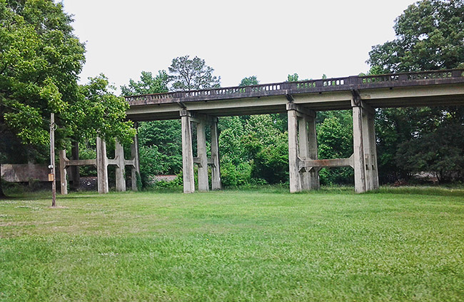 Concrete railroad bridge with supporting structure across field