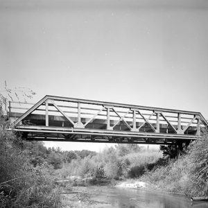 Side view of steel truss bridge over creek