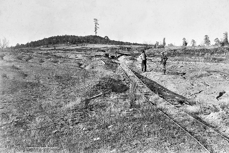 Two white men in large field with railroad tracks
