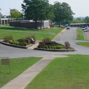 School campus with circle driveway landscaping parking lot trees and city skyline in background