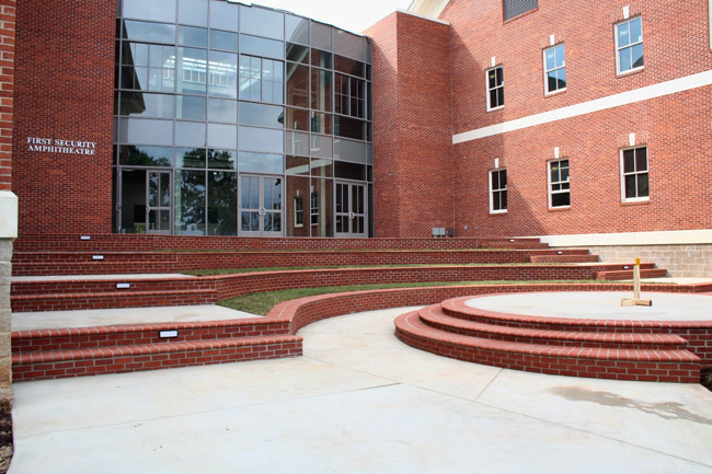 Multistory brick building with rounded glass entrance and steps