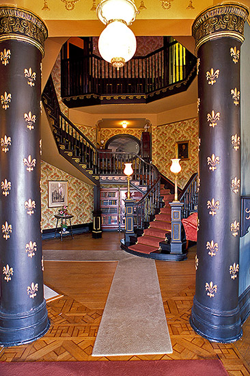 Spiral staircase beyond two painted columns with fleur-de-lis on them