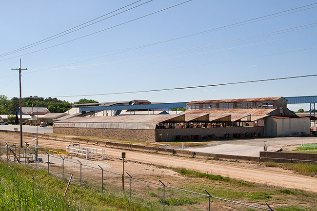 Industrial campus featuring warehouses roofed with sheet metal beyond a fence