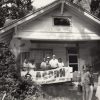 African-American men and women with Acorn banner on covered porch with film crew in the foreground