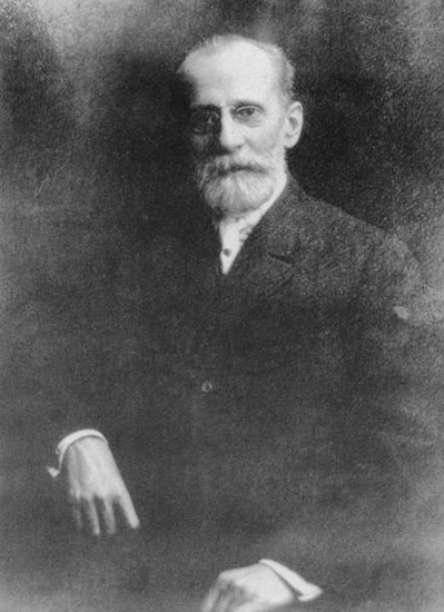 Older white man with beard mustache and glasses in suit