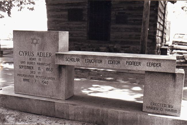 stone bench memorial monument for Cyrus Adler, described as "Scholar Educator Editor Pioneer Leader," in front of log cabin