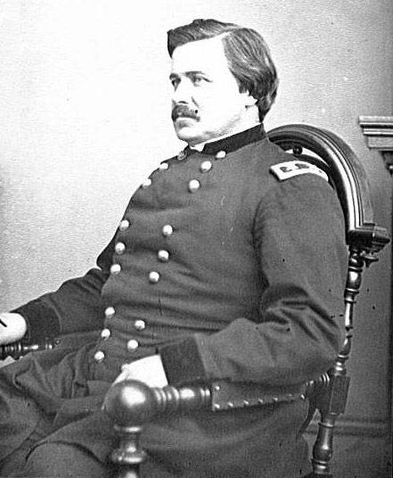 White man with mustache in military uniform sitting in chair
