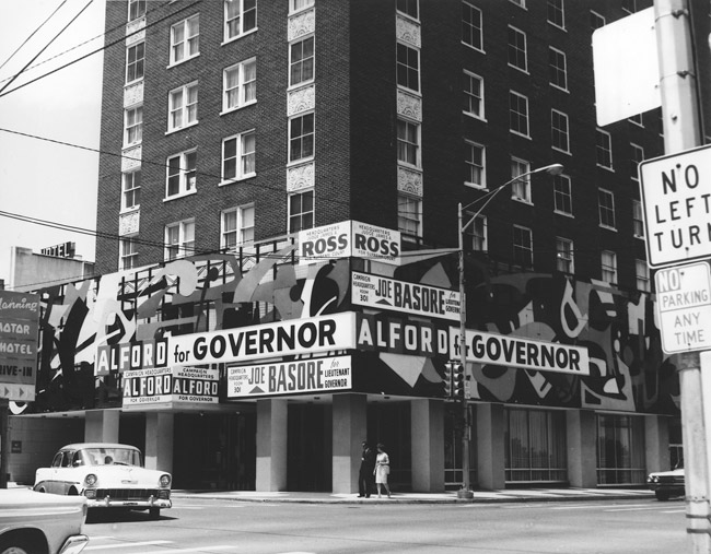 Tall brick building with square columns and political ad signs wrapped around it