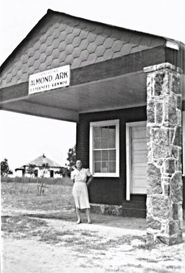 White woman standing under covered entranceway of single-story storefront with stone columns