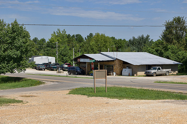 Single-story store on street with gravel parking lot