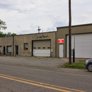Single-story two-bay garage building with metal siding and telephone pole on two-lane road