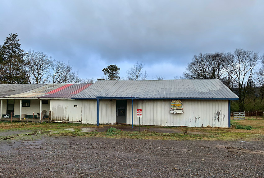 Dilapidated single-story building with gravel parking lot