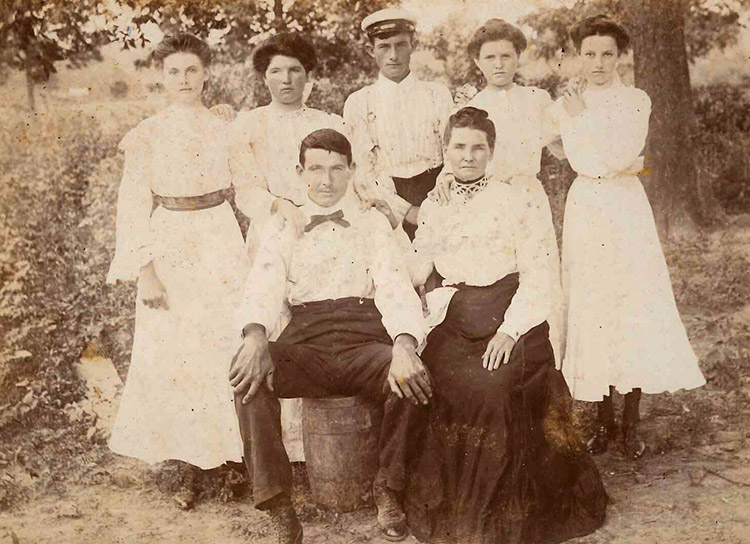 White man and woman sitting with four young white girls and white boy standing behind them