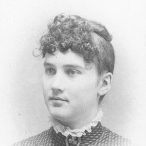 Young white woman with pulled up curly hair wearing lacy collar with horseshoe brooch