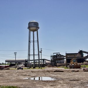 Industrial buildings and bull dozers on gravel with water tower