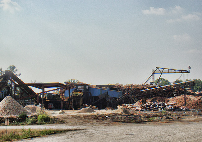 Mill buildings with piles of pine chips in the foreground