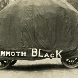 Four-wheeled vehicle covered in tarp with "Mammoth Black" written on it