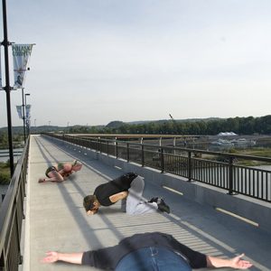 collapsed white woman and men superimposed on concrete bridge