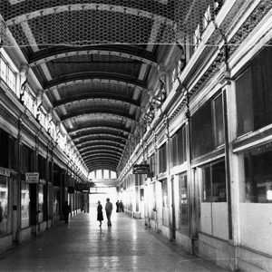 Arched hallway with rows of shops and signs with customers