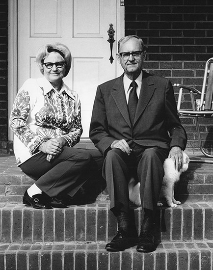 Older white woman and man with glasses sitting on brick steps