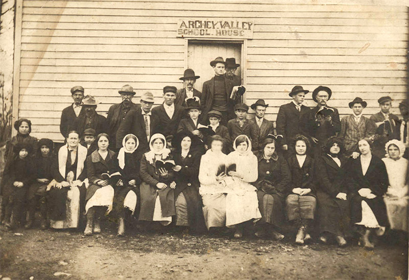 Group of white men and women outside "Archey Valley School House" building