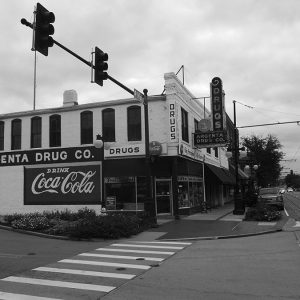 Two-story drug store on street corner with signs and traffic lights