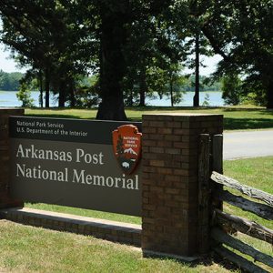 "Arkansas Post National Memorial" sign with trees and river