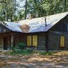Log cabin with covered porch and covered windows in forested area
