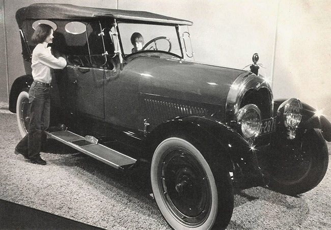 two people look inside an early twentieth century model car