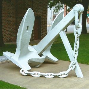 Large anchor and chain on concrete platform on court house lawn with brick buildings in the background