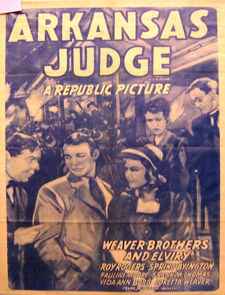 White men in suits and women in dresses with crowd behind them and "Arkansas Judge" text on faded paper