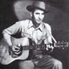 White men with hat in western clothing playing an acoustic guitar