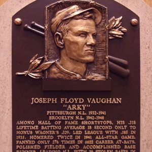 Bust of white man in baseball cap with bats and leaves on plaque with text