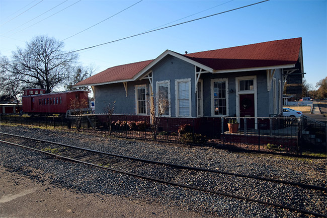 Single-story train station building with tracks and train car