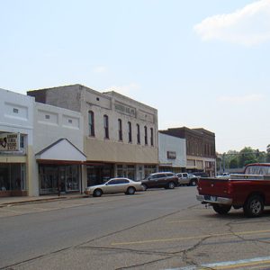 Street with two-story storefronts and parked cars