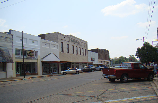 Street with two-story storefronts and parked cars