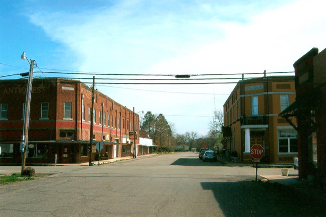 four way intersection with stop signs and two story brick buildings