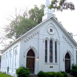 Church with a steeple, white walls, arched windows, and arched doorways