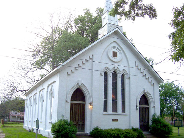 Church with a steeple, white walls, arched windows, and arched doorways