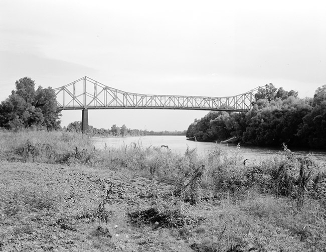 Side view of steel truss bridge over river